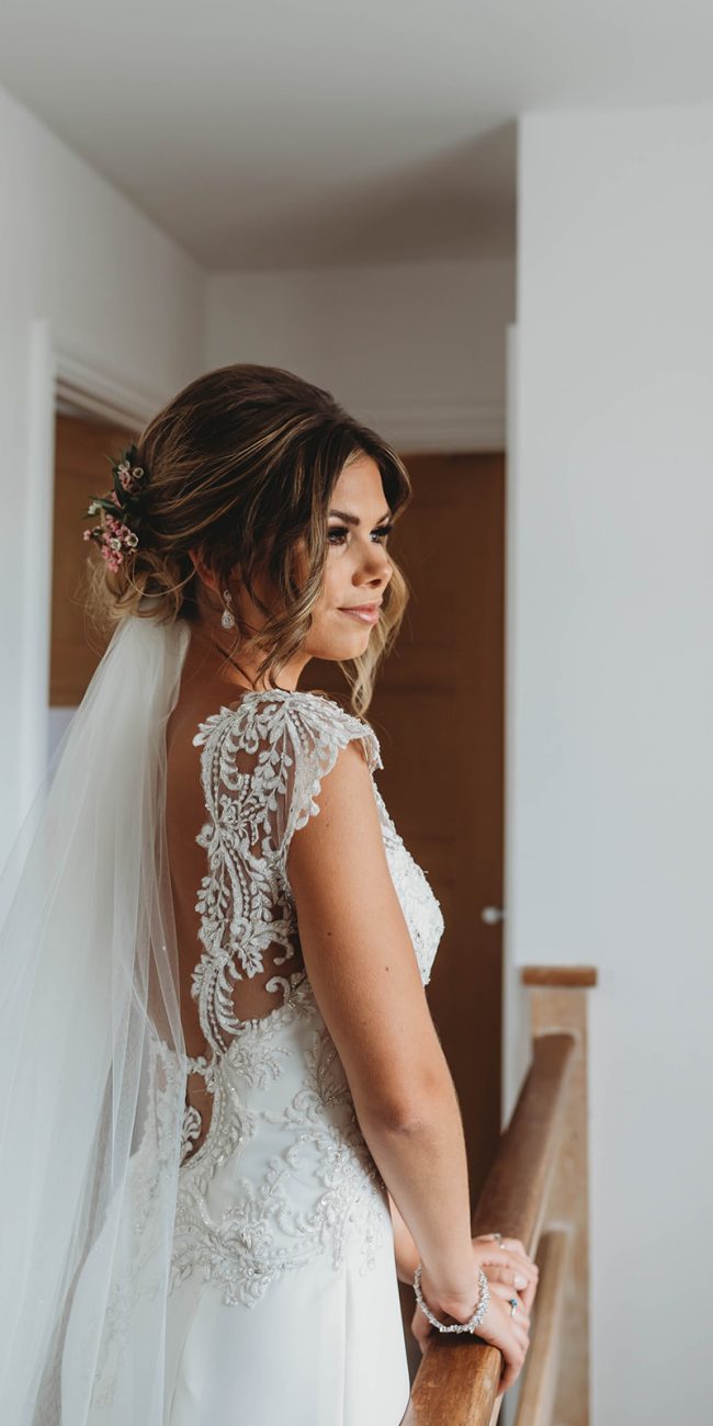 Bride wearing her wedding dress with detailed back and a long veil