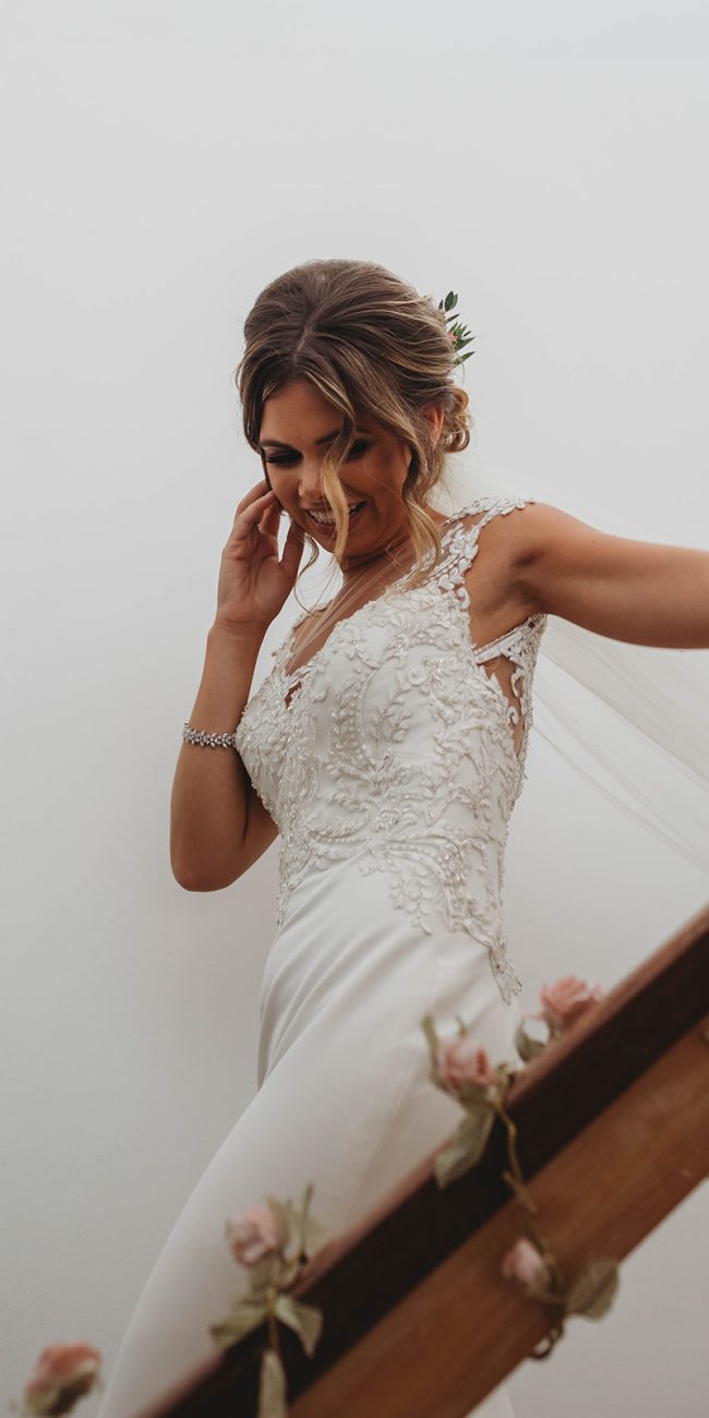 Bride wearing her wedding dress and veil walking down the stairs so her father can see her for the first time