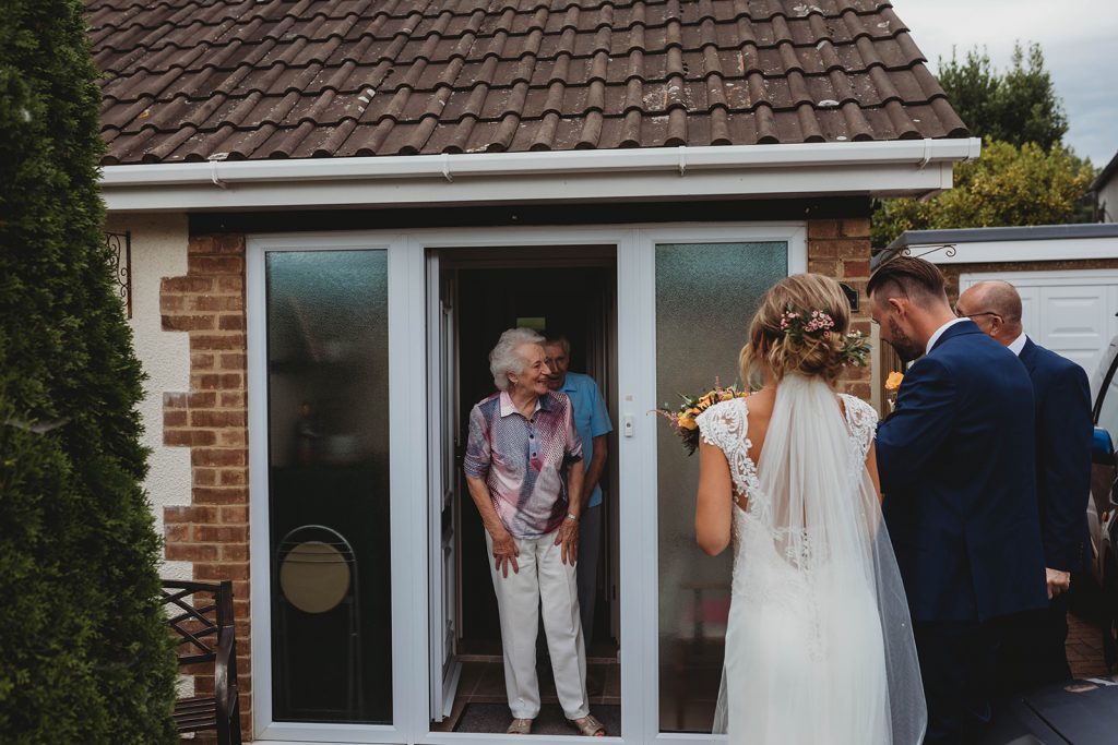 Bride + groom visiting family wearing their wedding attire that couldn't attend their wedding due to COVID restrictions