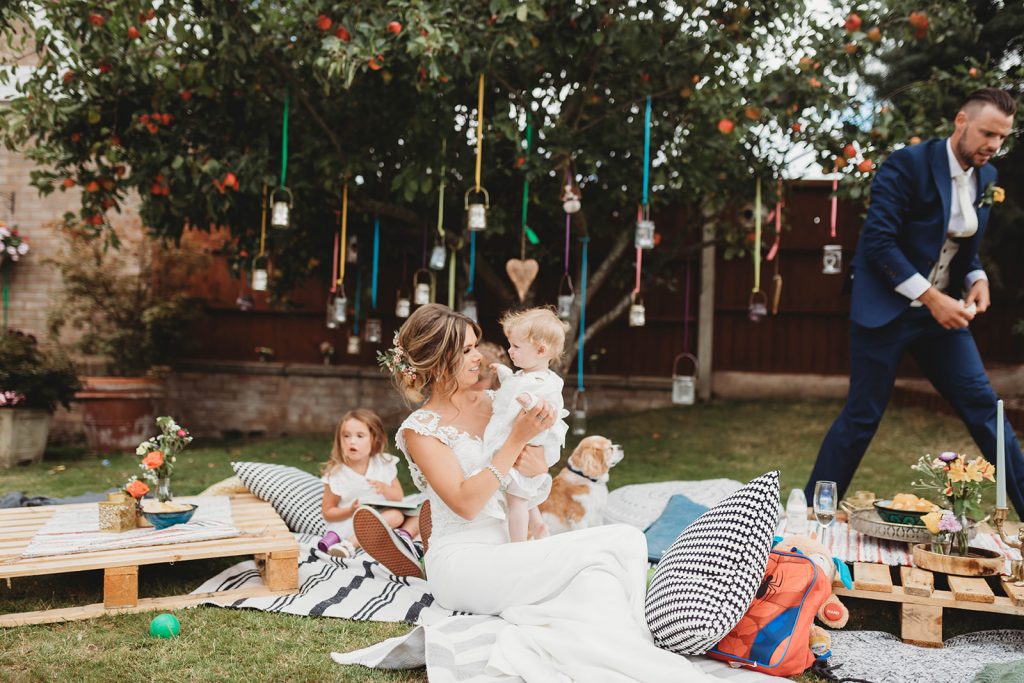 Bride sitting in her wedding dress holding s young guest during her wedding day