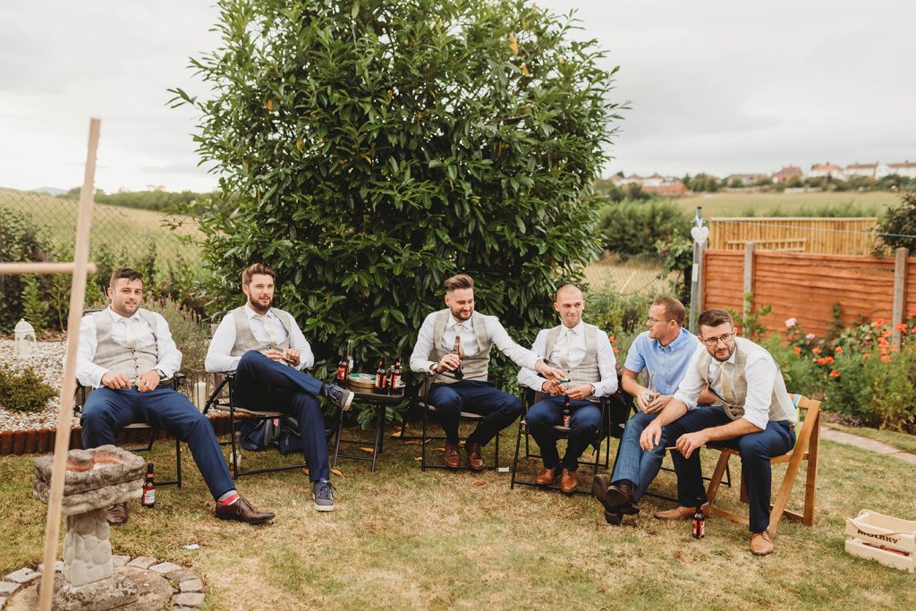 Wedding guests sitting in a garden enjoying a relaxed afternoon with some drinks