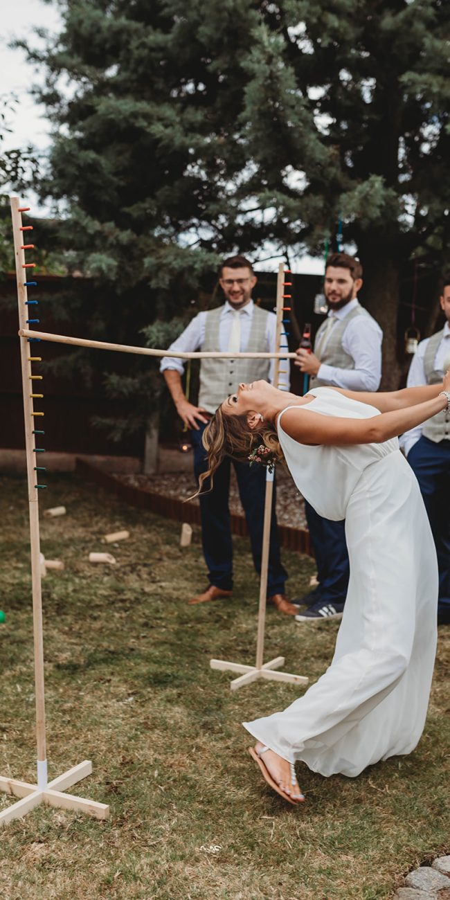 Bride in her wedding dress doing the limbo in her garden on her wedding day