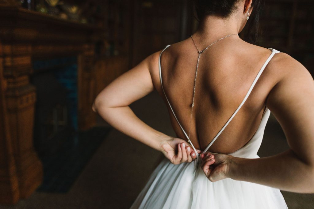 Clos up of bride doing up her wedding dress on her wedding day