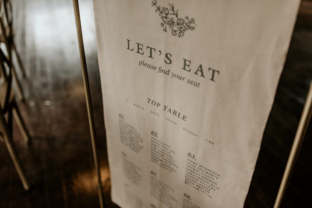 Close up of textured fabric hung on gold frame for wedding table seating plan for country house wedding