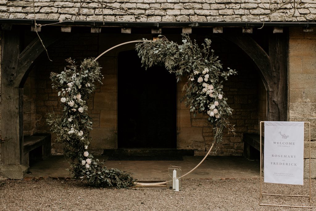 Green foliage covered wedding moongate with gold wedding arch for outdoor wedding ceremony