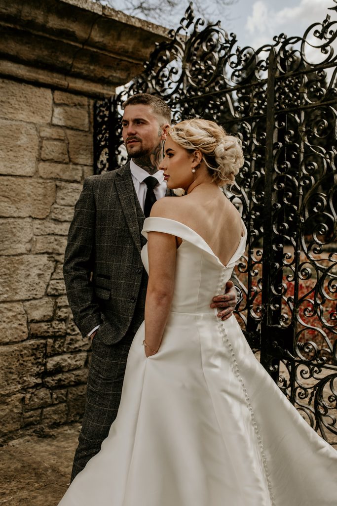 Wedding day couple portrait. The bride wears a off the shoulder dress with pockets