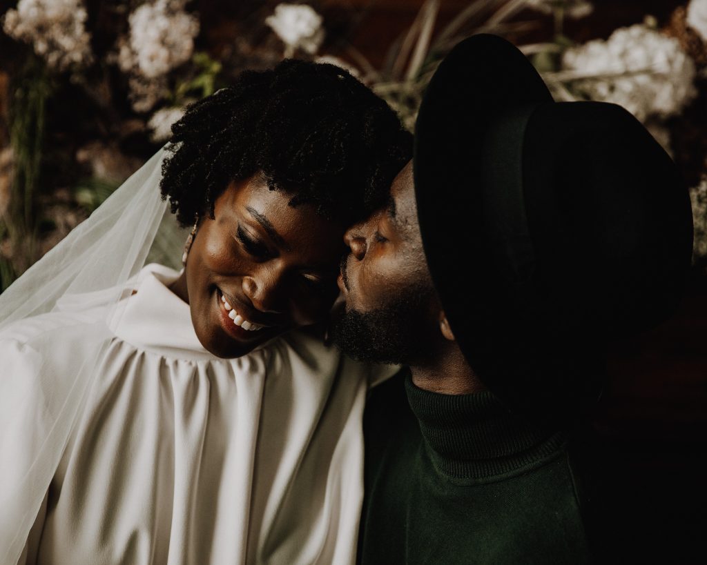 Newly married wedding couple smiling, The bride wears a Moonchild high neck wedding dress with a long veil