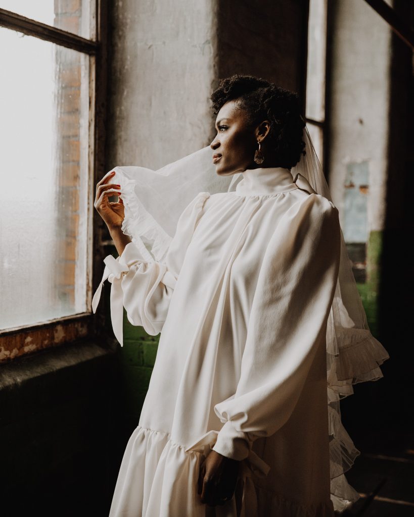 Beautiful micro wedding bridal style wearing a short Moonchild wedding dress with high neck and long wedding veil