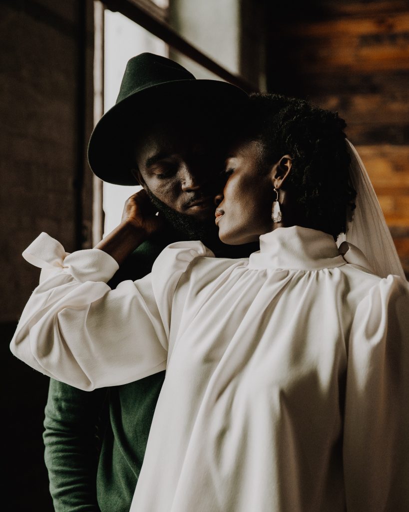 Newly married bride and groom in tender embrace. The bride gently holds her husbands face as he stands behind her