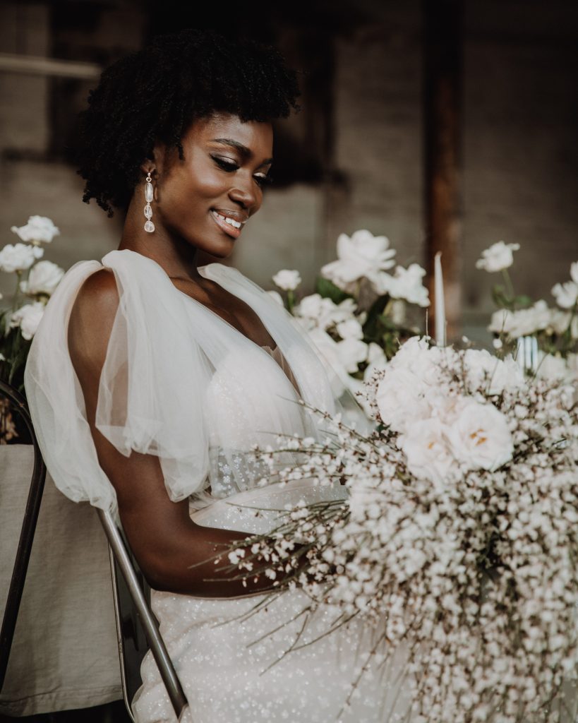 Bride in white sparkly Berta wedding dress gazing at her white wedding bouquet