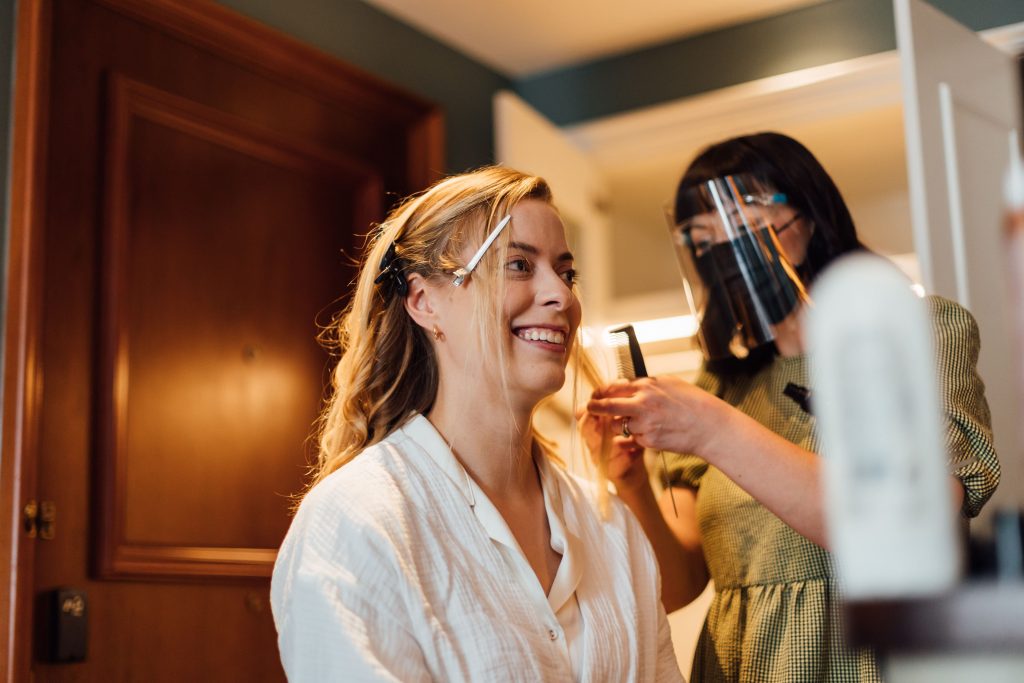 Bridal prep for city wedding bride with hair stylist wearing visor
