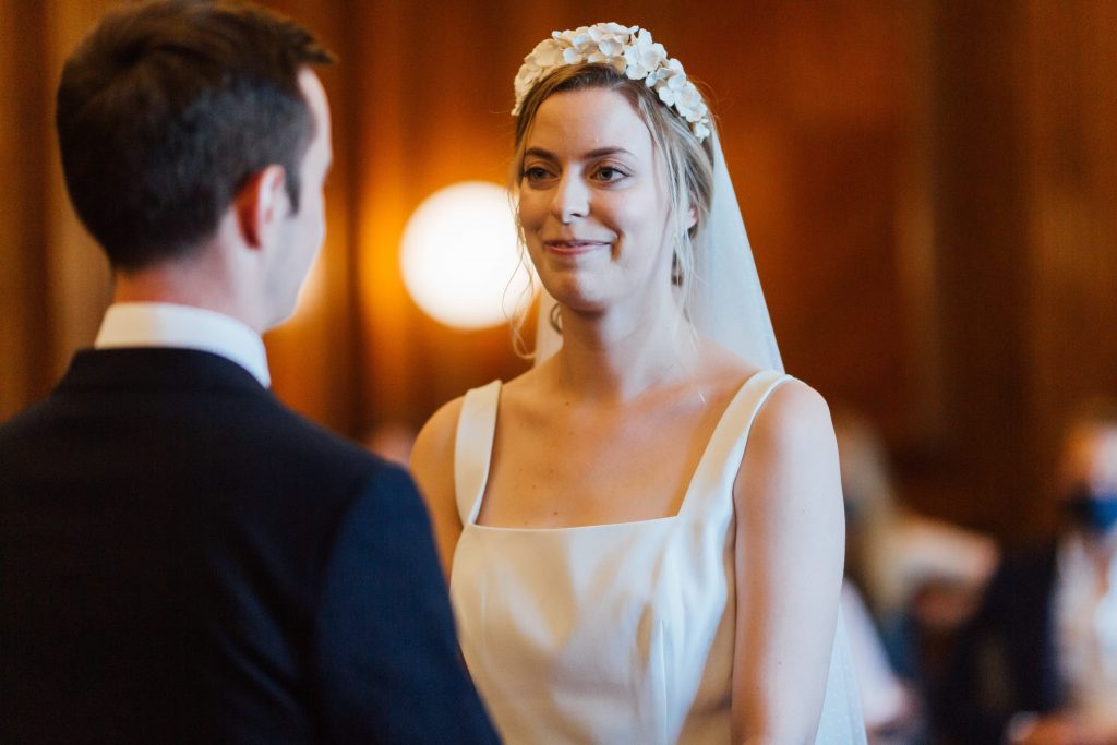Bride to be wearing sleeveless summer wedding dress with flower crown and veil about to say her vows
