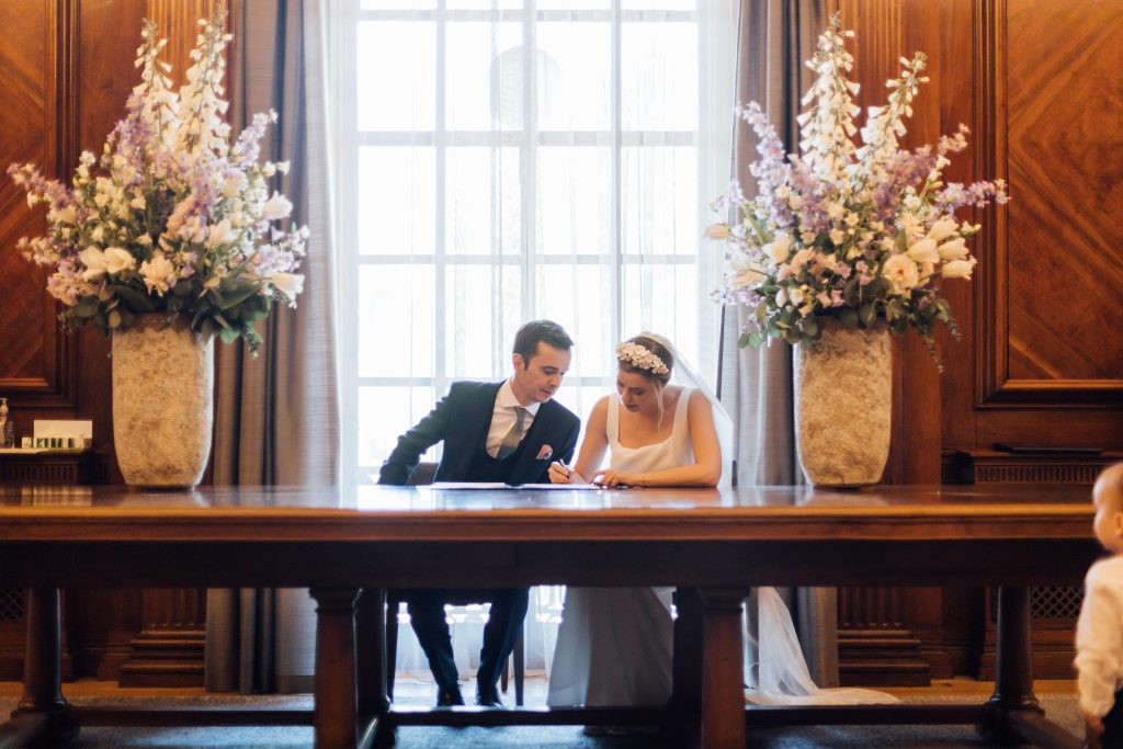 Just married bride and groom sign the registry book as they officially become husband and wife in city micro wedding