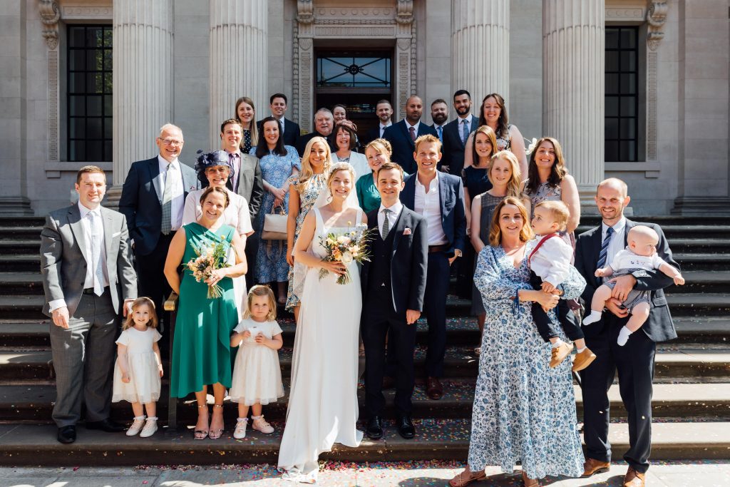 Wedding photo of 30 wedding guests outside the Old Marylebone Town Hall ceremony venue