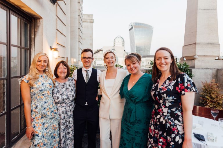 Bride and groom pose with wedding guests during their city rooftop summer micro wedding celebrations