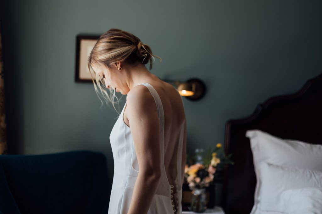 Bridal prep morning for city micro wedding bride as she puts on her wedding dress