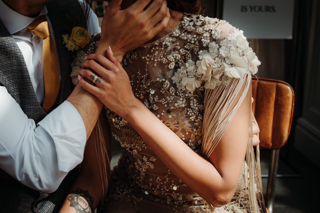 Close up of wife and husband on their wedding day. The groom gently cups his wife face a she gently holds his hand wearing her wedding ring