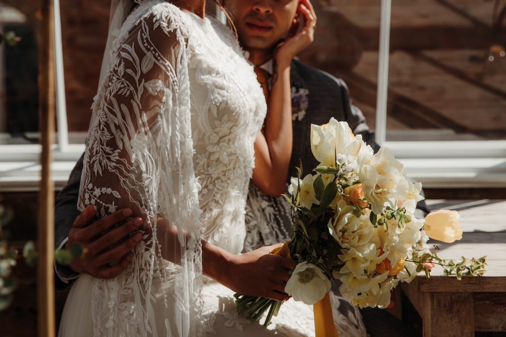 Newly married bride sits on her husband's lap and cradles his face in her hand