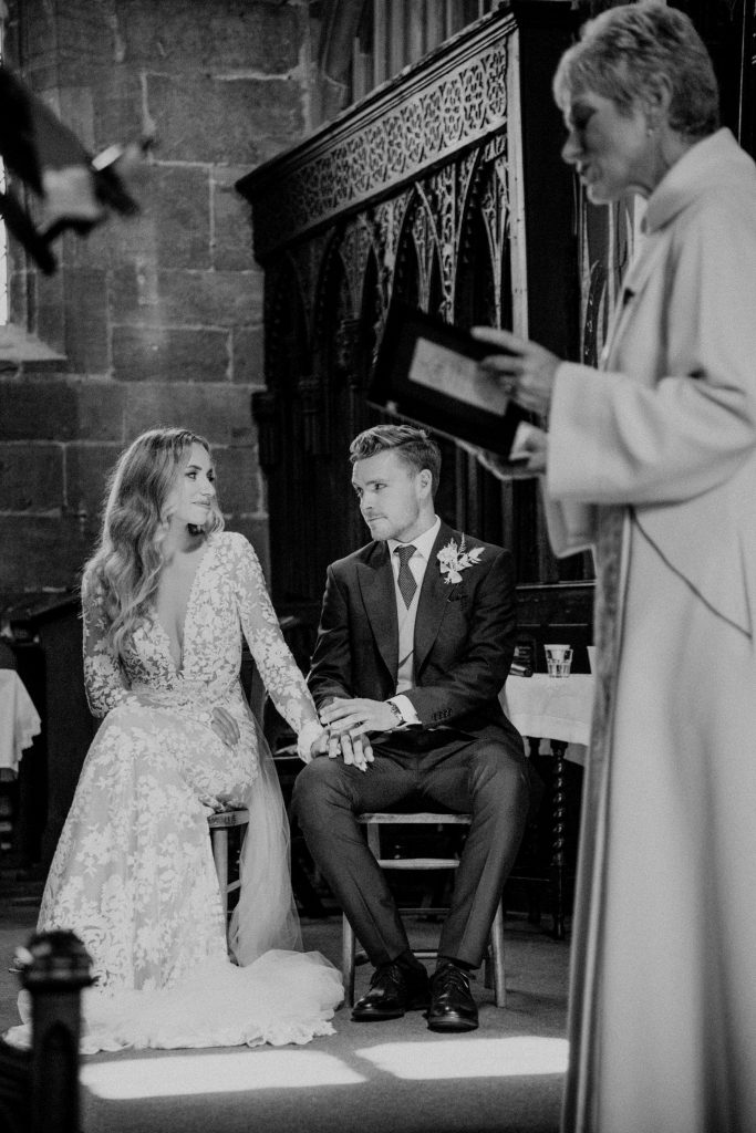 Bride and groom hold hands during emotional wedding church service