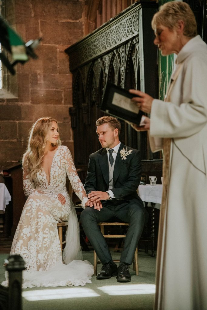 Bride and groom hold hands during emotional wedding church service