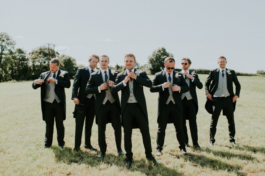Groom and his groomsmen enjoying the sunshine during summer barn wedding