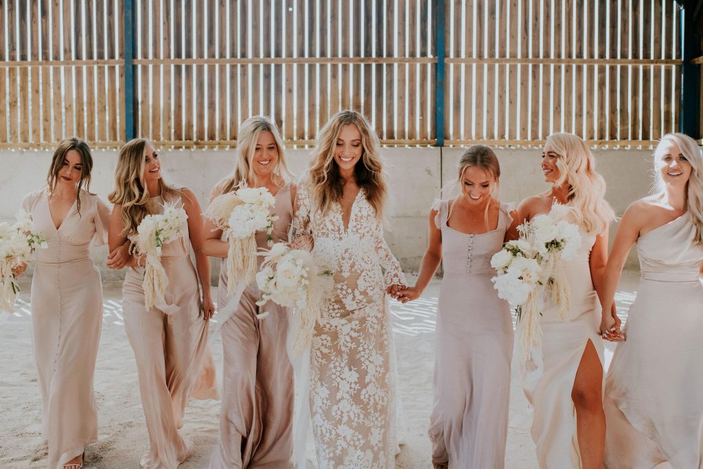 Stunning bridal party in pink bridesmaids dresses with white bouquets for boho festival wedding