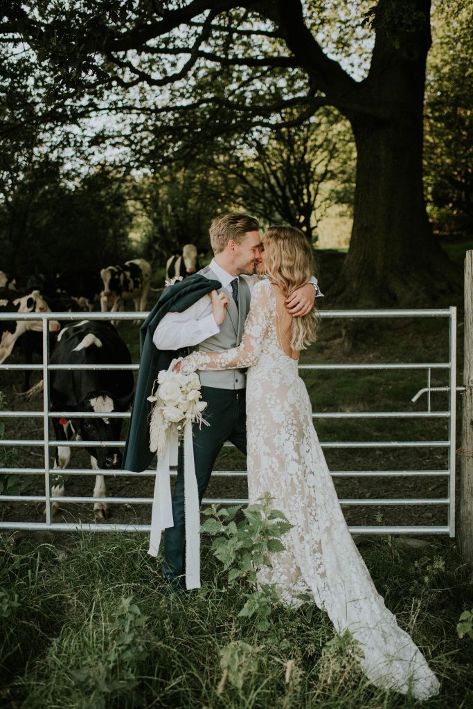 Romantic kiss for newly married bride and groom in summer barn wedding