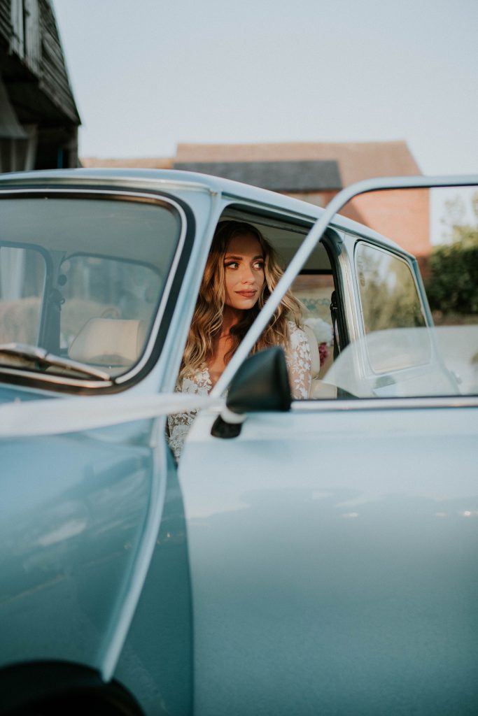 Beautiful bride in blue wedding car arriving at her wedding venue