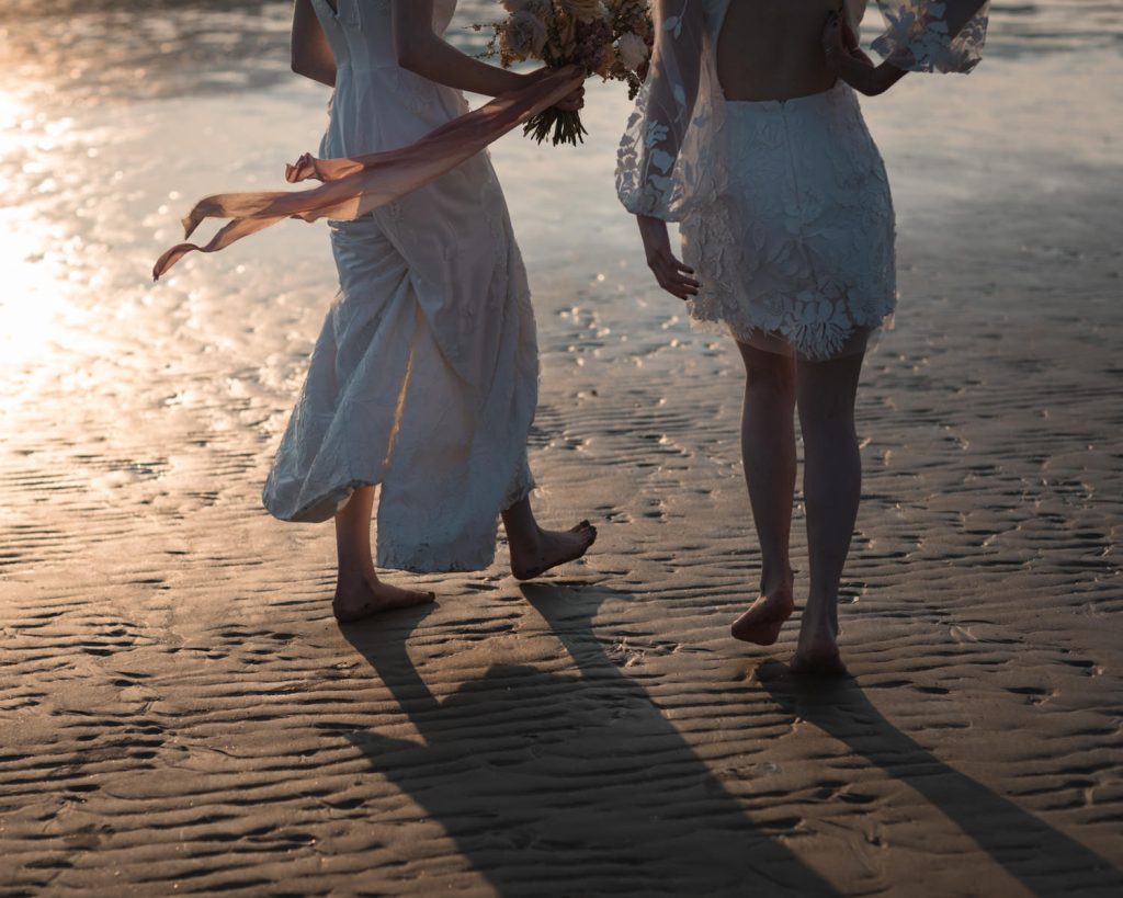 Two newlywed brides in sunset beach wedding elopement