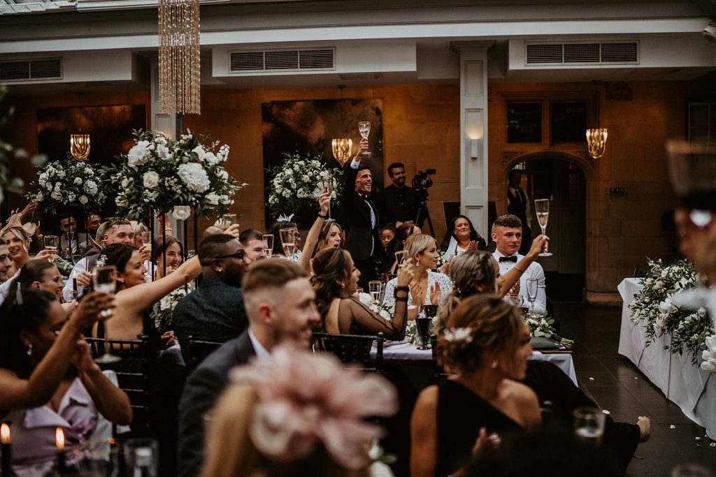Wedding guests raise a glass of bubbly to toast the newly married bride and groom during wedding speeches