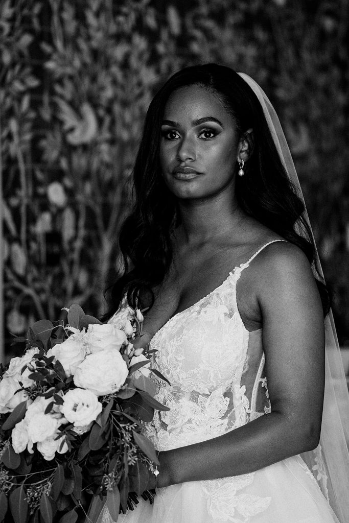 Beautiful bride in a detailed lace Enzoani wedding dress with long veil and white wedding bouquet