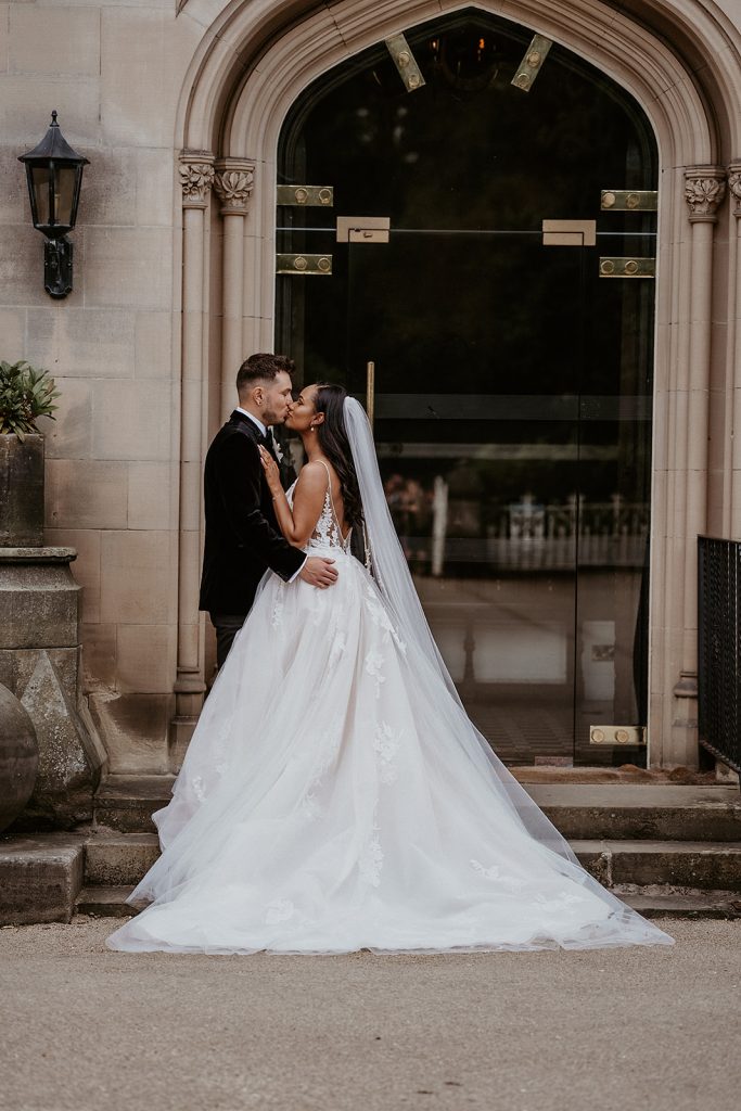 Newlyweds kiss at the front entrance to their private country manor wedding venue