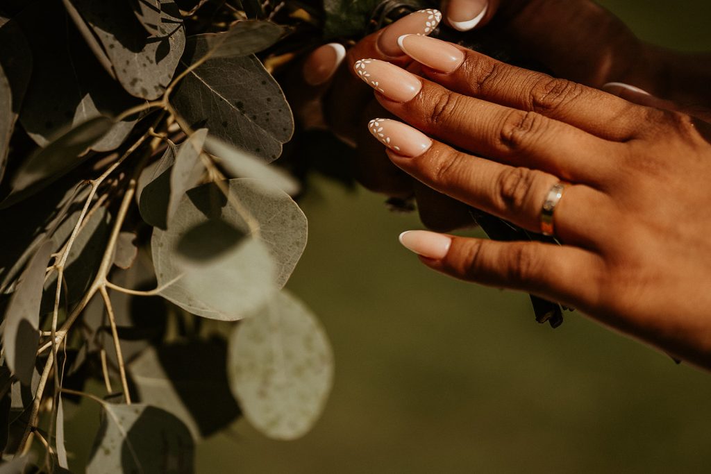 Close up of a bride's manicured nails and wedding band