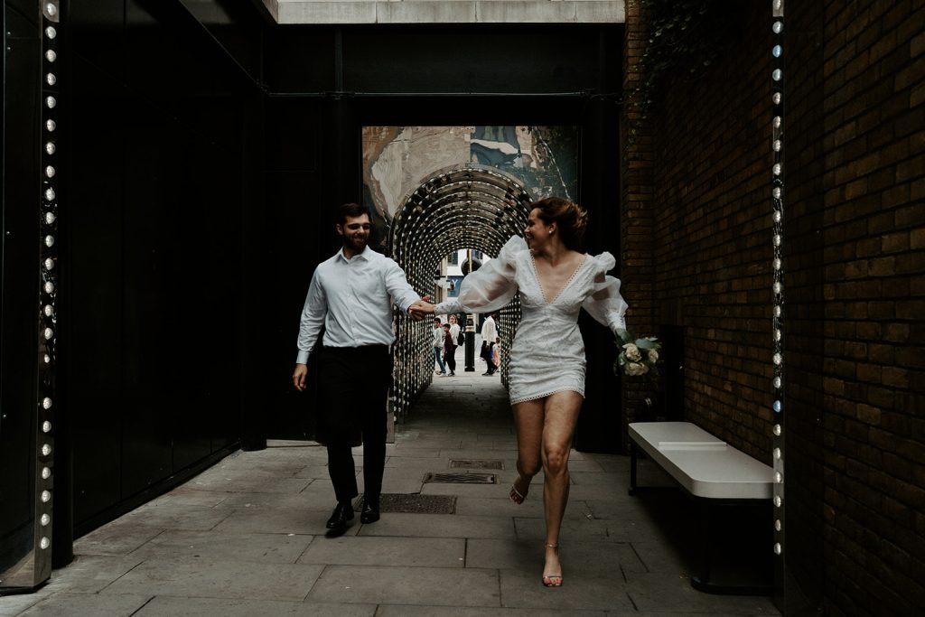 Bride and groom run through the streets of London during their city elopement