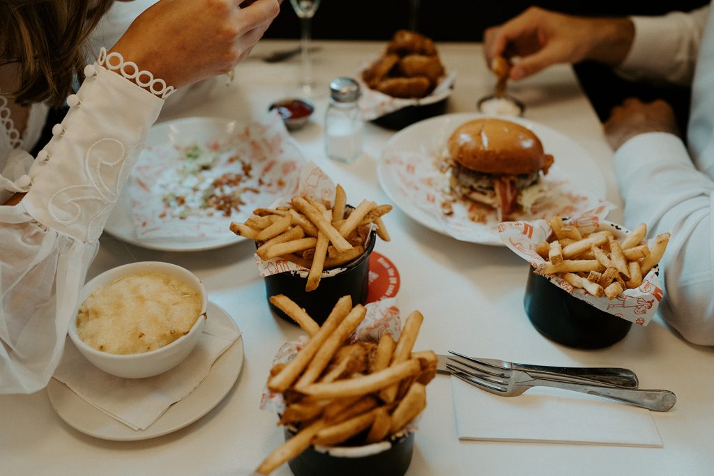 Newly married bride and groom enjoying burgers, fries and Champagne during their city elopement