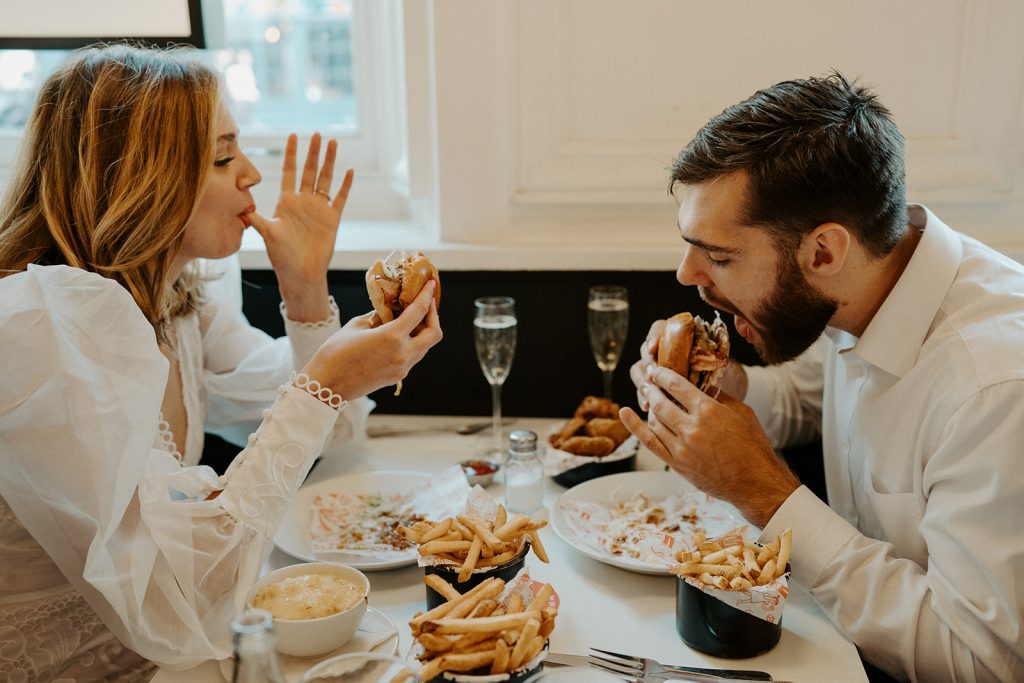 Bride and groom enjoy burgers, fries and Champagne during their city elopement