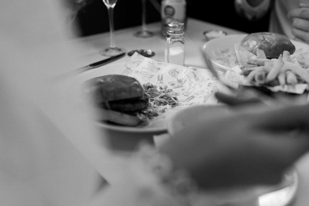 Newly married bride and groom enjoying burgers, fries and Champagne during their city elopement