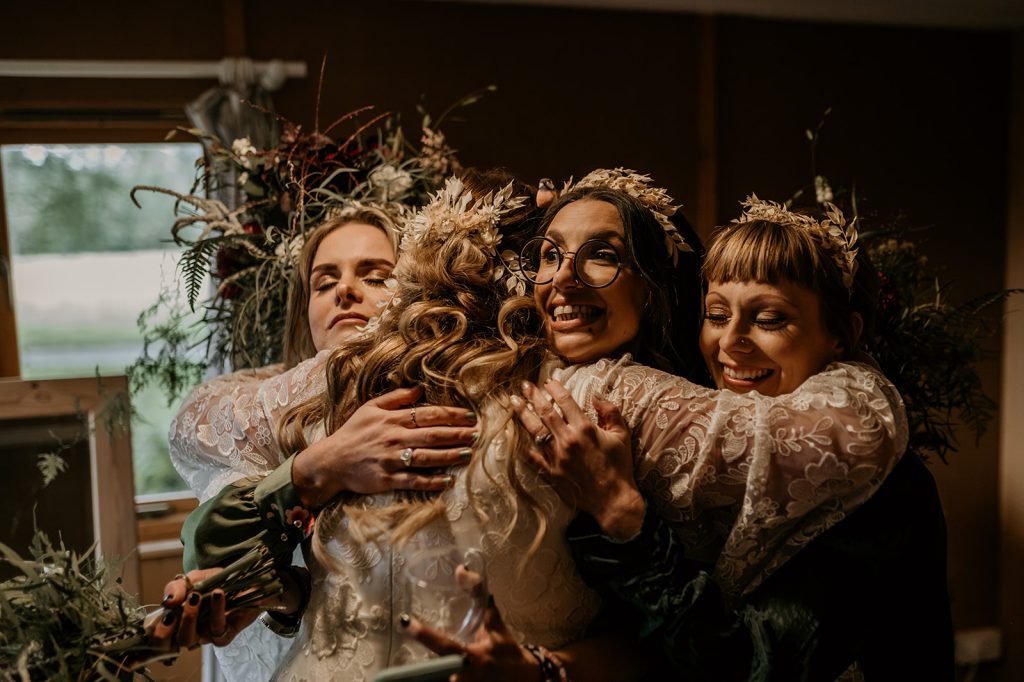 An emotional embrace between a bride and her bridesmaids just before the ceremony