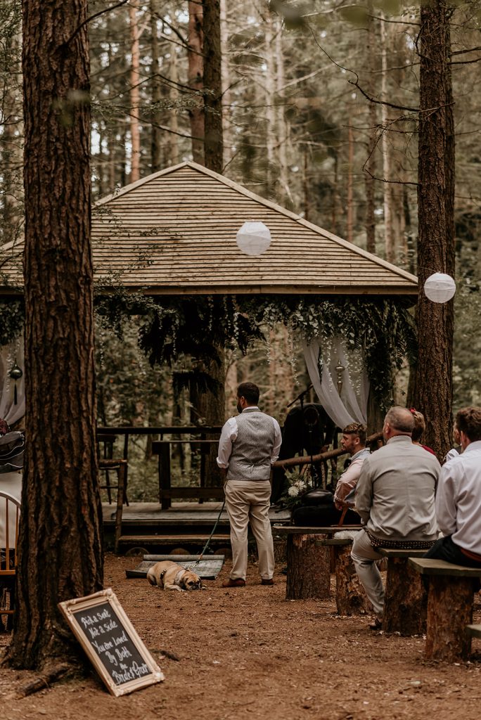 A groom in a waistcoat stands patiently waiting for his soon to be wife to walk up the aisle