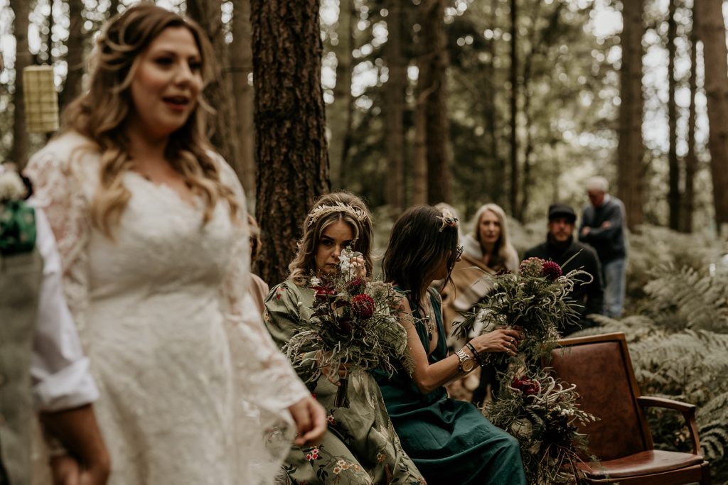 Bridesmaid wipes away tears during emotional outdoor woodland ceremony