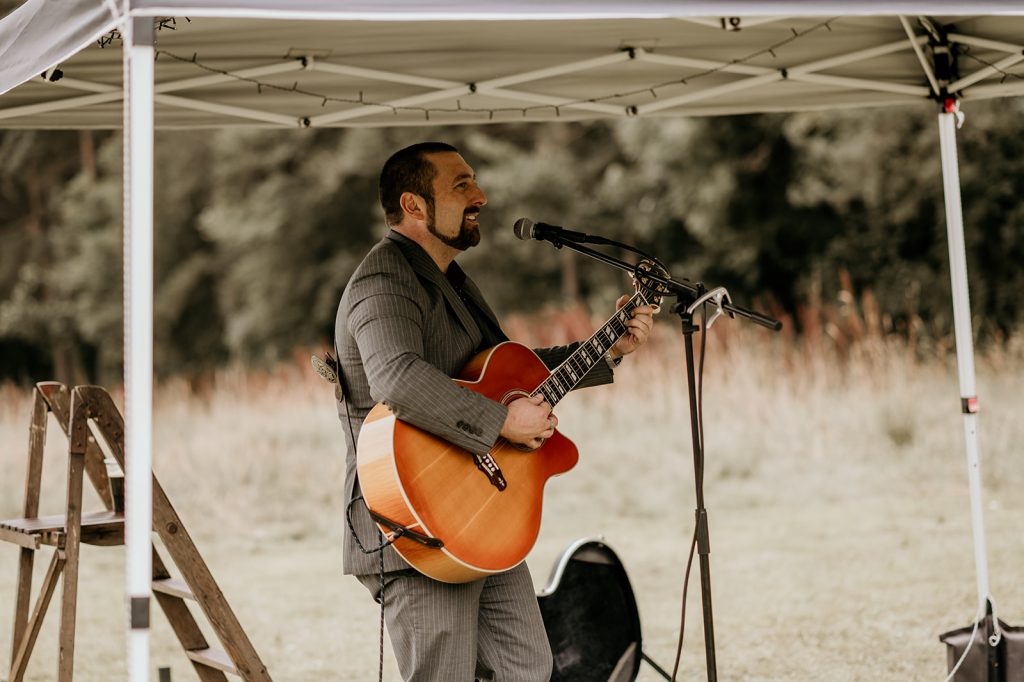 Wedding singer performing outside during woodland wedding reception