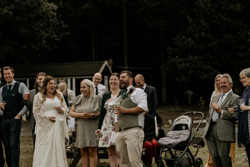 Bride and groom and their guests enjoying outdoor speeches during their informal and laid back outdoor wedding