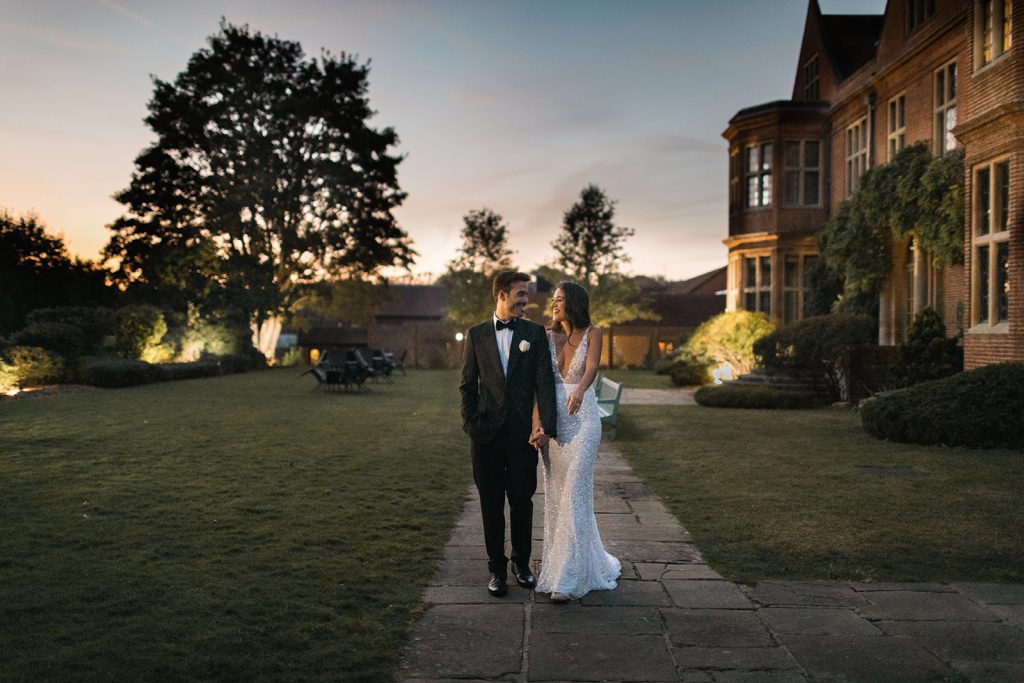 Newly married husband and wife stroll around the gardens during dusk on their wedding day