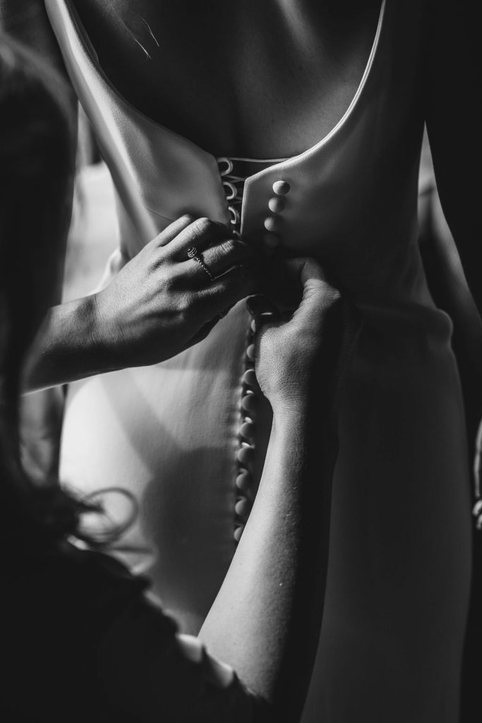 Bride Grace is helped into her Suzanne Neville gown during bridal prep on the morning of her wedding