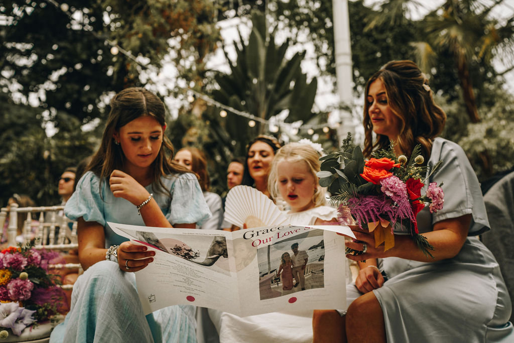 Bridesmaids and guests sing from personalised song sheets during Grace + Elliott's Autumn wedding ceremony