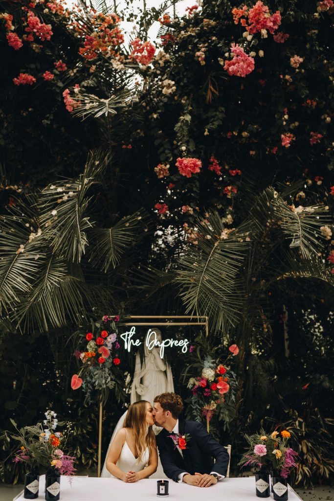 Personalised neon signage for The Duprees set against a floral backdrop at Sefton Park