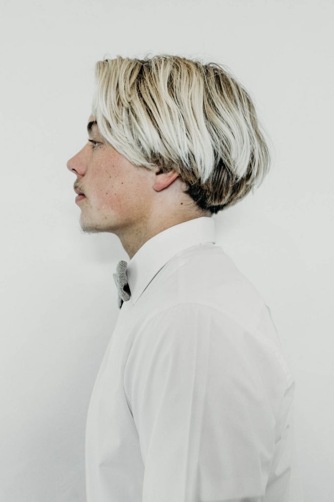 A modern groom in a white shirt and bow tie