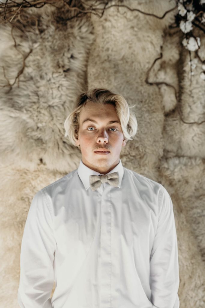 A modern groom in a white shirt and bow tie