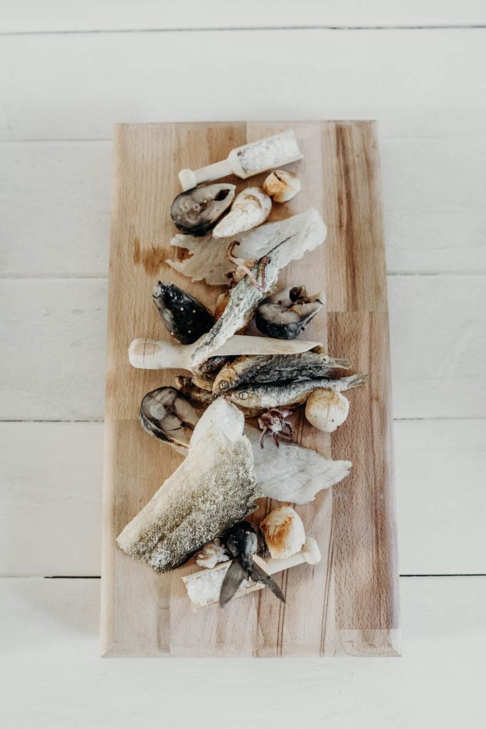 A fish board of sprats, cod skin, salted cod, scallops, squid + pickled mackerel for modern barn wedding