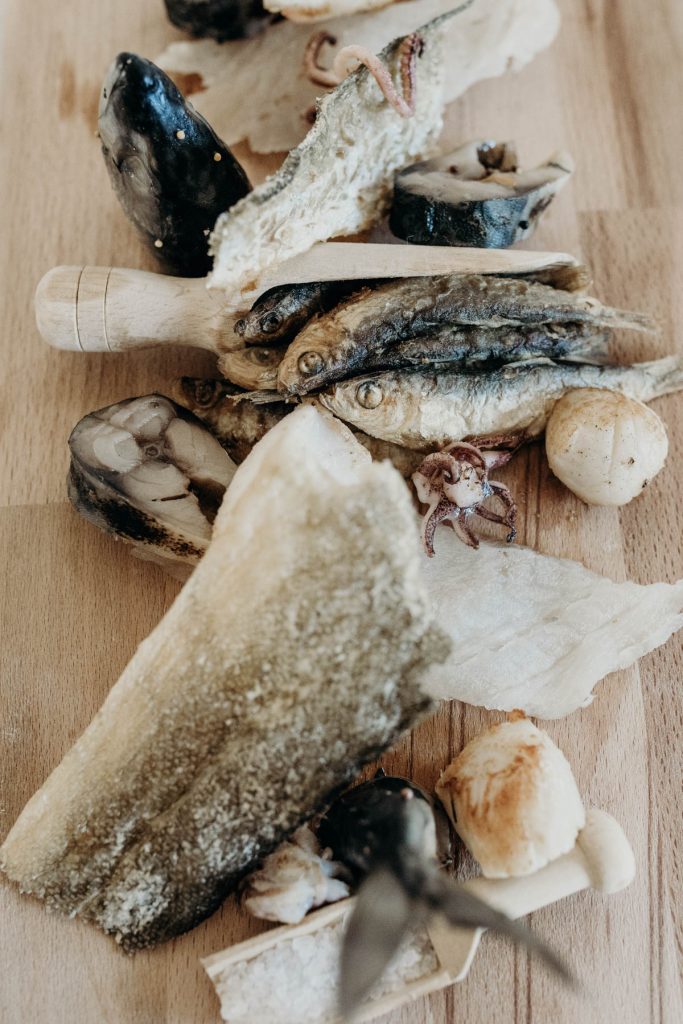 A fish board of sprats, cod skin, salted cod, scallops, squid + pickled mackerel for modern barn wedding